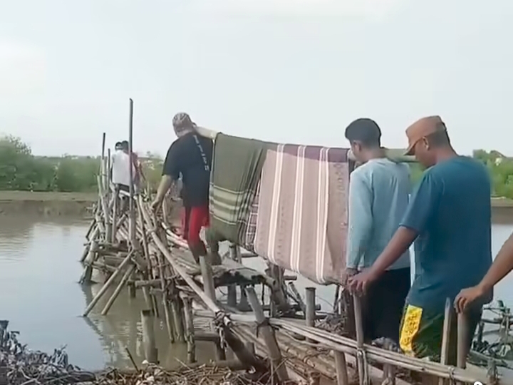 Tangkapan layar : Warga menandu jenazah hanya dengan sarung yang diikat pada dua batang bambu panjang